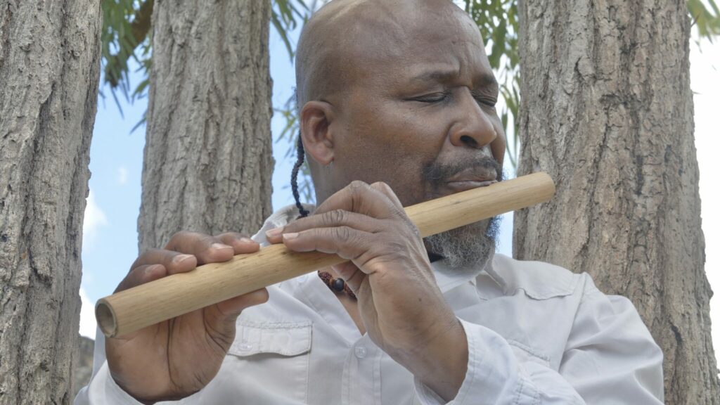 Igo Drané joue dans une flûte taillée dans du bambou